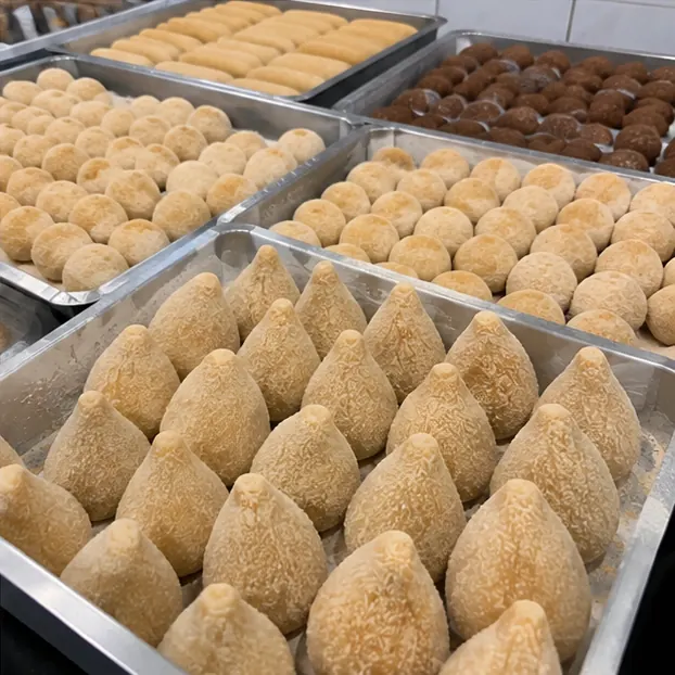 Bandejas de coxinha, bolinha de queijo, kibe e enroladinho empanados antes do congelamento